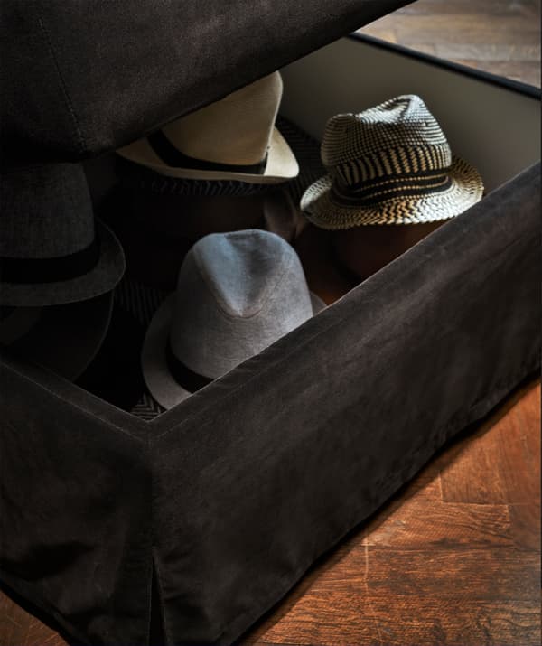 Repose-pieds FÄRLÖV gris foncé servant de rangement à des chapeaux.