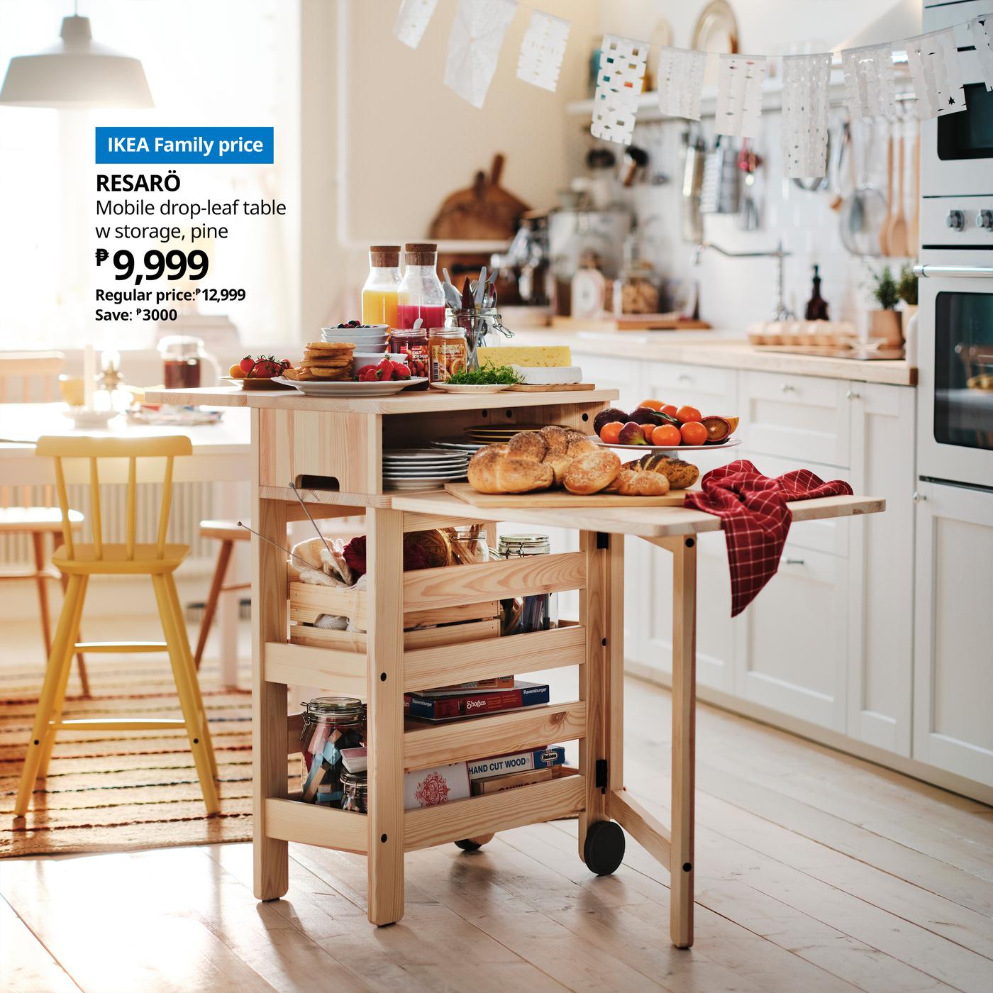 RESARÖ mobile drop-leaf table stocked with breakfast food and tableware placed beside a dining table in a light kitchen.