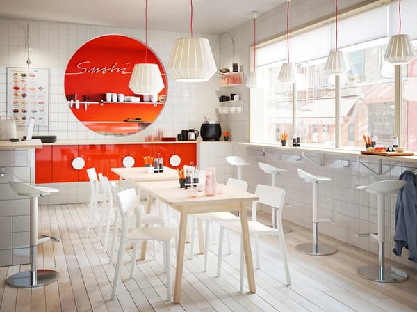 Restaurant à sushi blanc et orange meublé avec des tabourets de bar blancs et des chaises basses JANINGE de IKEA.
