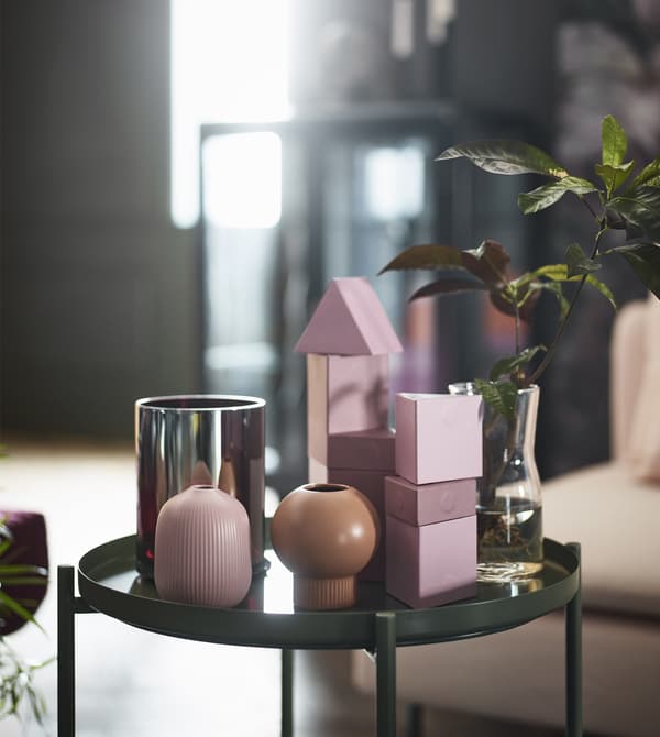 Resting on a green tray table are two GRADVIS vases in natural and pink stoneware with round, organic shapes.