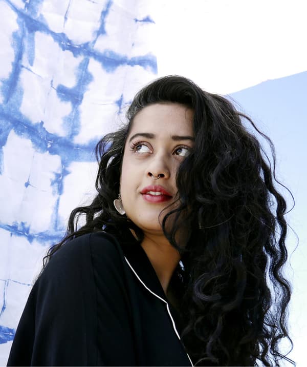 Retrato de Akanksha Deo, cun fondo de tea azul e branco.