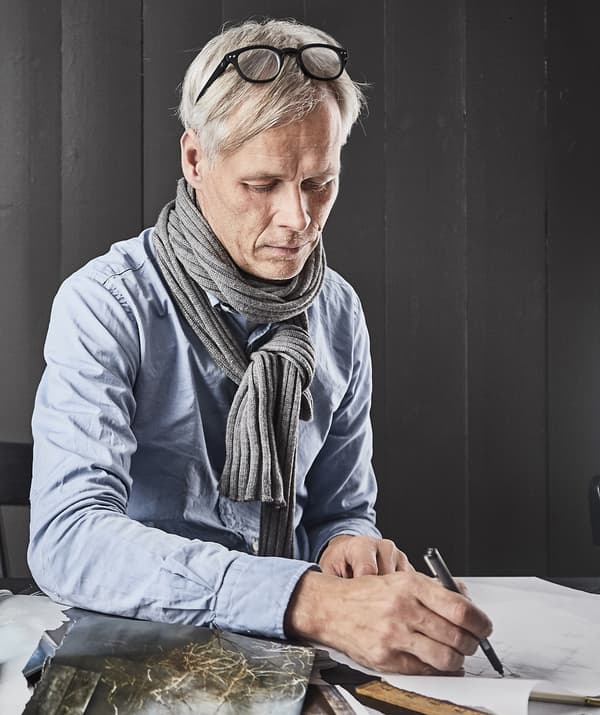 Retrato de Hans Blomquist dibujando un boceto sobre una mesa.