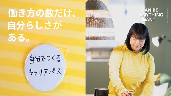 リビングルームの床の上に広げられた列車のセットで遊ぶ父親と娘を、母親ともう一人の娘が見ている。