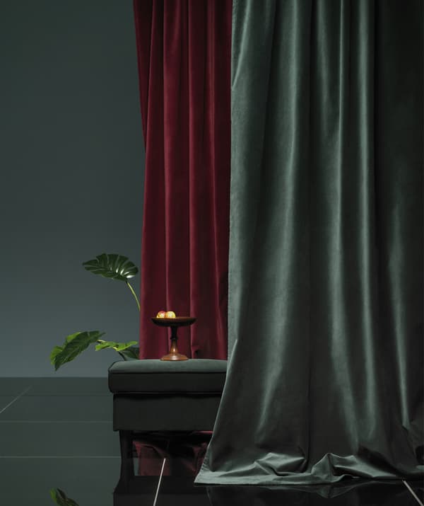 Rideaux de velours rouge foncé et verts drapés autour d'un repose-pieds.