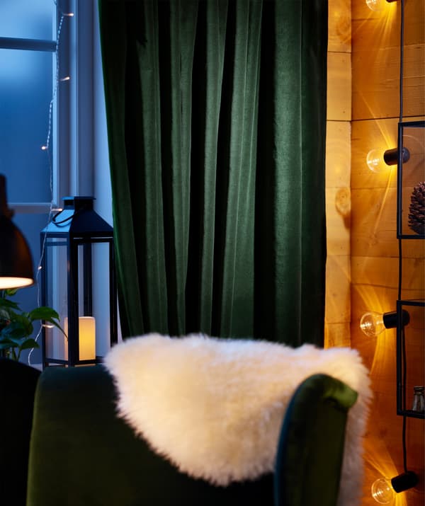 Rideaux en coton vert foncé IKEA SANELA derrière une chaise en peau de mouton.