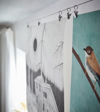 RIKTIG curtain hooks with clips holding art posters in a dorm room.