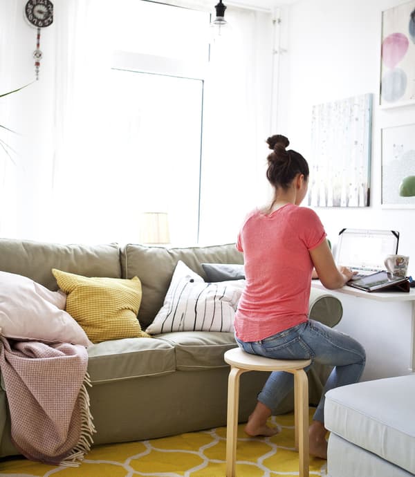Ringa working at her drop-leaf table in a bright living room.