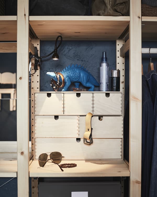 Ripiano di uno scaffale in legno con una mini cassettiera piena di accessori da teenager.