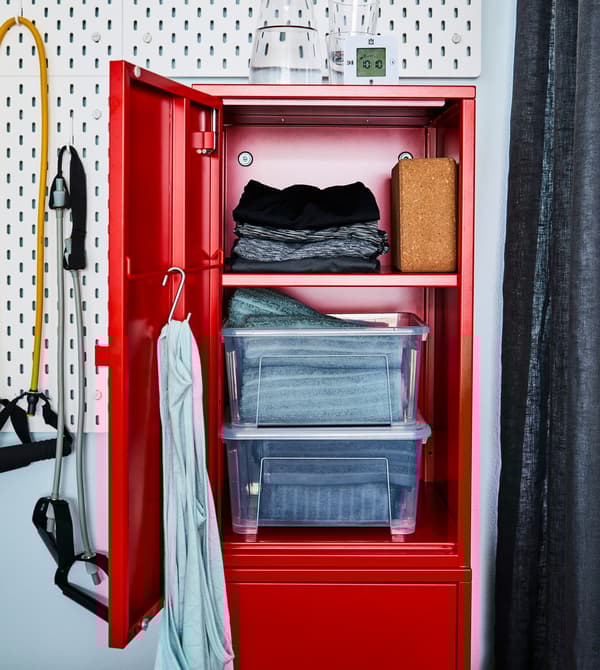 Rode locker waarvan de bovenste deur openstaat, waarachter opgevouwen handdoeken en sportkleding te zien zijn.