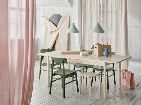 RÖNNINGE extendable table with its extension in use is placed in a dining room context with an ongoing wrapping activity.