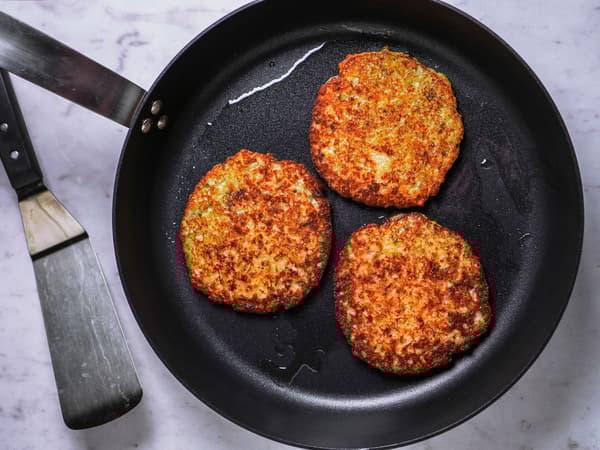 Rösti werden für das Rezept Rösti mit Birnen, Preiselbeeren und gerösteten Walnüssen in einer Pfanne angebraten.