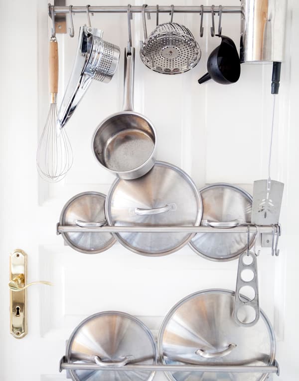 Roestvrijstalen deksels en eetgerei staan uitgestald (binnen handbereik) met wandrails in deze keuken