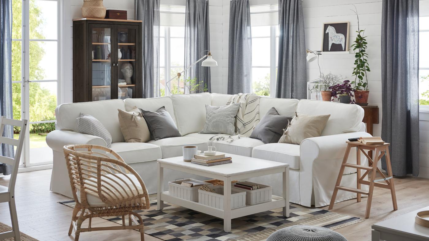 Rohový díl pohovky EKTORP v bílé barvě a bílý konferenční stolek HAVSTA ve světlém obývacím pokoji.