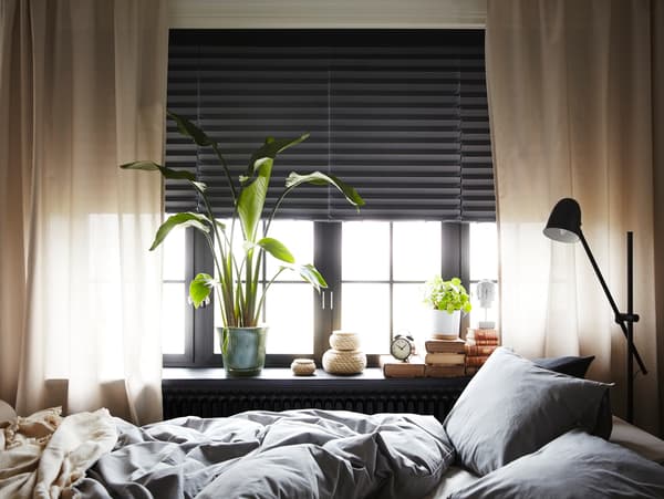 Roletne za blokiranje svetlosti tamnosive boje s naborima pokrivaju polovinu sva četiri prozora. Sofa ležaj koji je namešten kao krevet nalazi se napred.