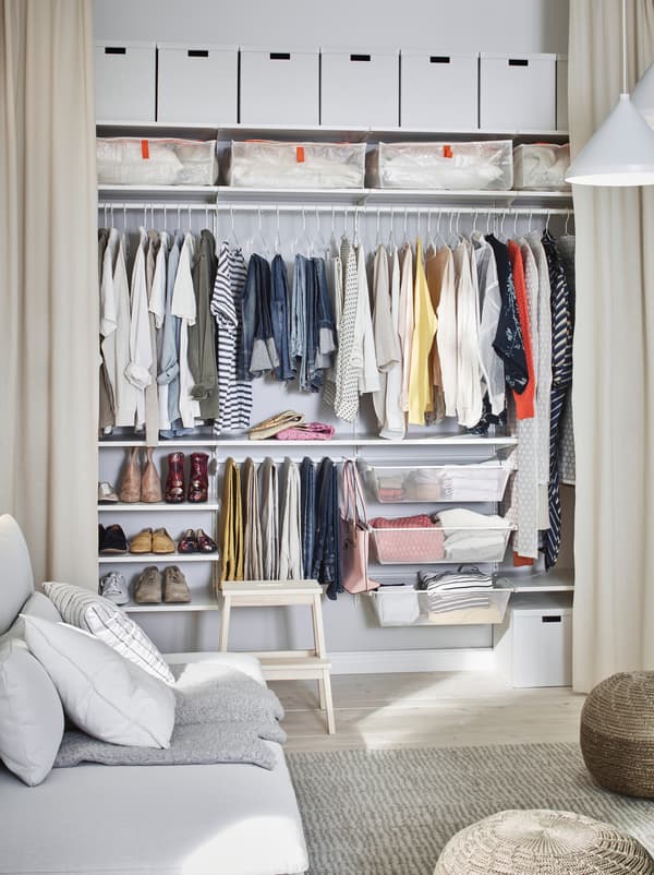 Room where one wall is fitted with open, floor-length curtains, revealing a wall-wide BOAXEL wardrobe arrangement.