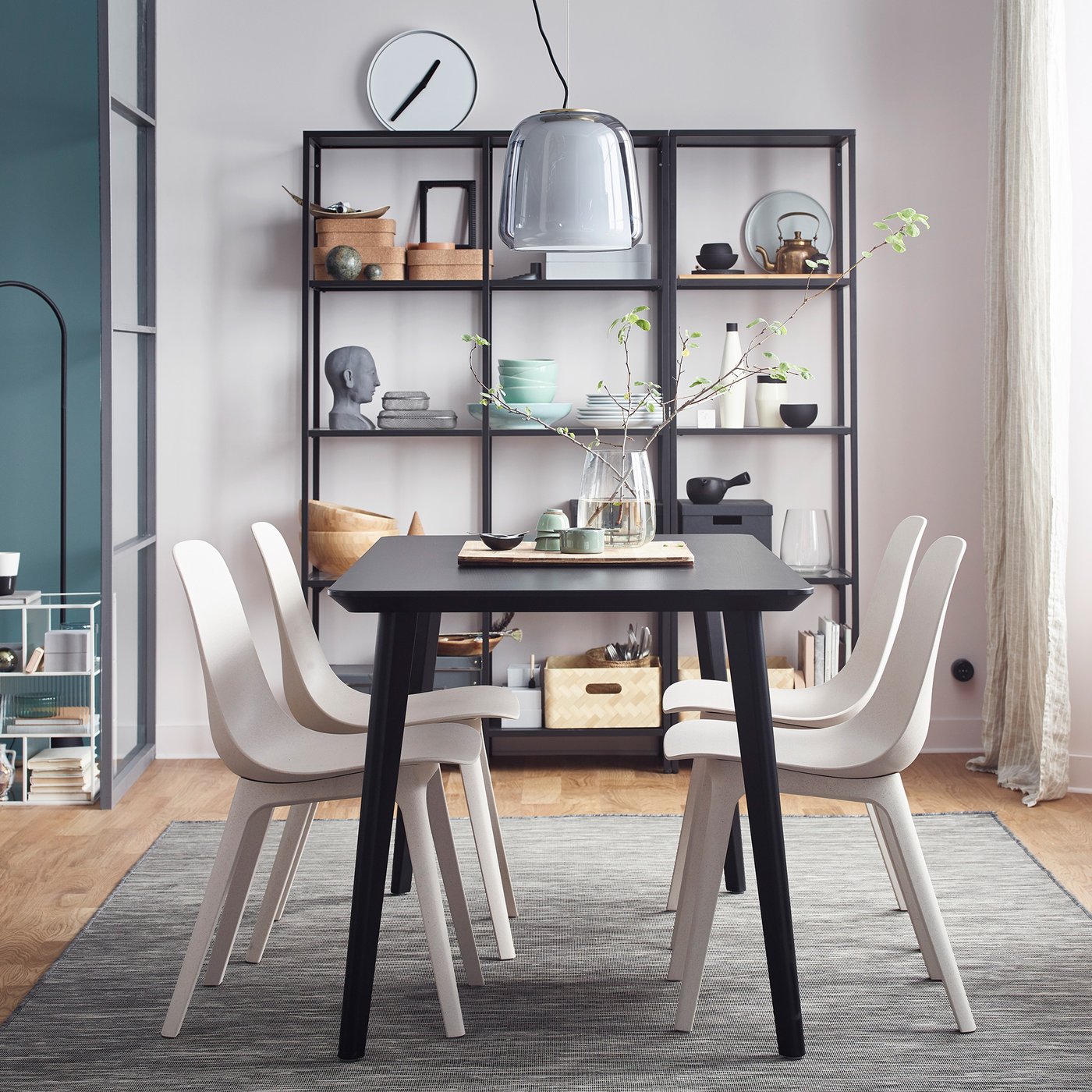 Room with LISABO table and four chairs plus a ceiling lamp hanging above. Shelves filled with ornaments to the rear and a window with long curtains to the right.