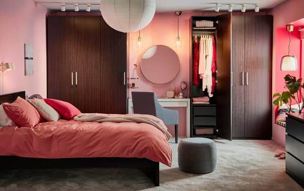 Rosarotes Zimmer mit einem Bett, rosaroter Bettwäsche und rosa Dekoration.