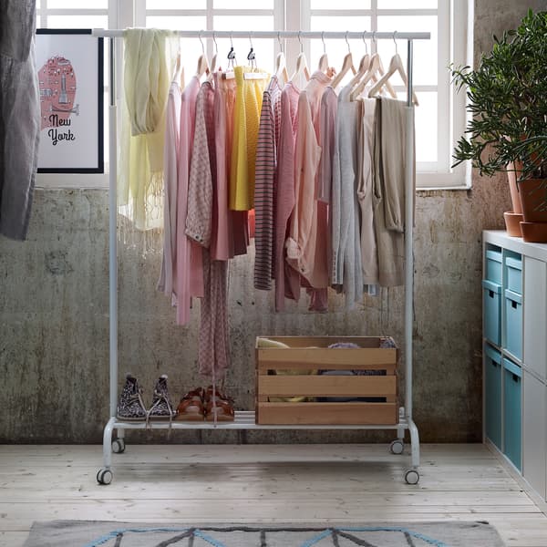 Roupa de cores pasteis nun colgadoiro branco RIGGA que se atopa nunha habitación na que entra luz.