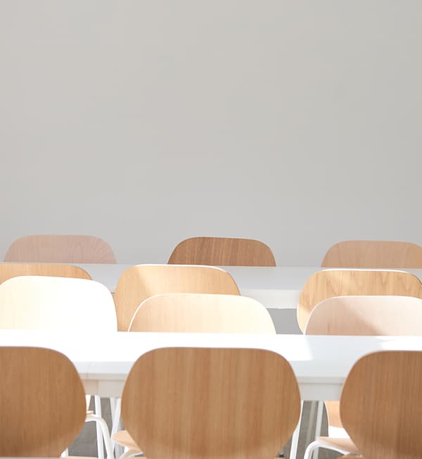 Rows of white tables and wooden chairs.
