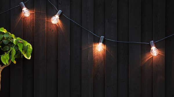 Rozsvícená světelná závěsná LED řetěz SVARTRÅ dotvářející příjemnou atmosféru na terase.