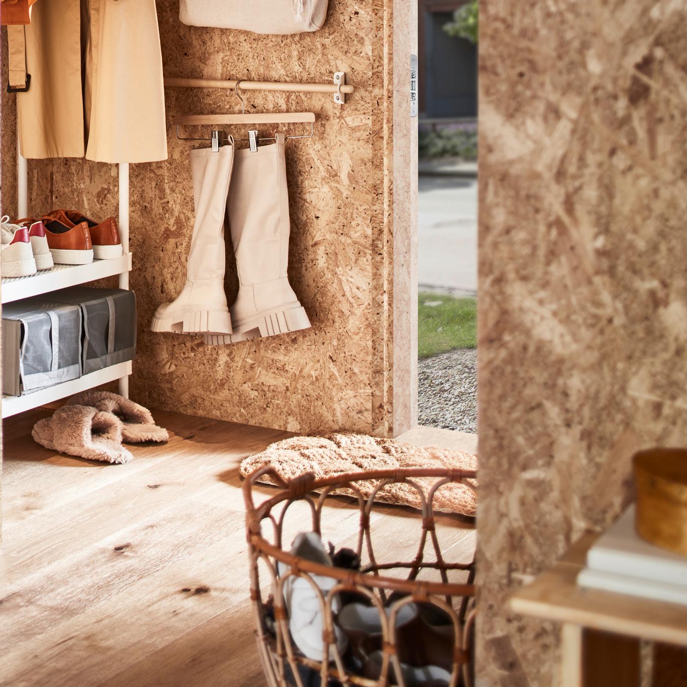 Ruang depan yang mempunyai rak kot dengan storan kasut berwarna putih, bakul rotan berisi kasut serta rel dengan but pada penyangkut skirt.