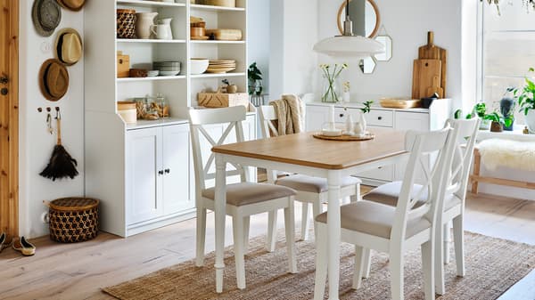 Ruang makan dengan meja buatan kayu oak/berwarna putih, empat kerusi berwarna putih, ambal jut dan dua kabinet tinggi berwarna putih dengan dua pintu di setiap satunya.