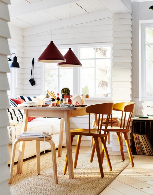 Ruang makan yang mempunyai sofa berwarna putih dengan bantal dan meja makan dengan beberapa bangku boleh tindan KYRRE yang dibuat daripada kayu birch.