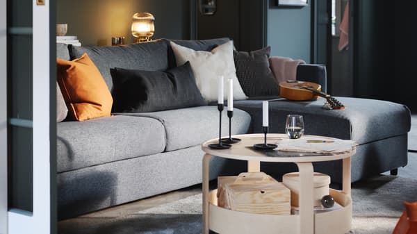 Ruang tamu dengan dinding berwarna hijau yang mempunyai sofa tiga tempat duduk dengan chaise longue VIMLE berwarna kelabu sederhana dan meja kopi kayu birch BORGEBY.