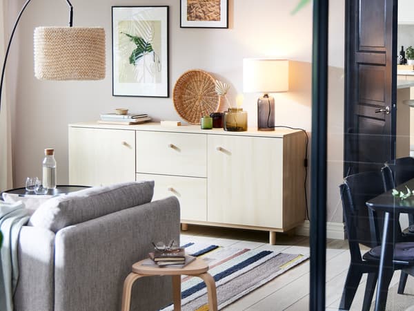 Ruang tamu yang cerah yang mempunyai hiasan dan aksesori di atas saidbod ERSNÄS kesan kayu birch yang terletak bertentangan dengan sofa SÖDERHAMN berwarna kuning air-coklat.
