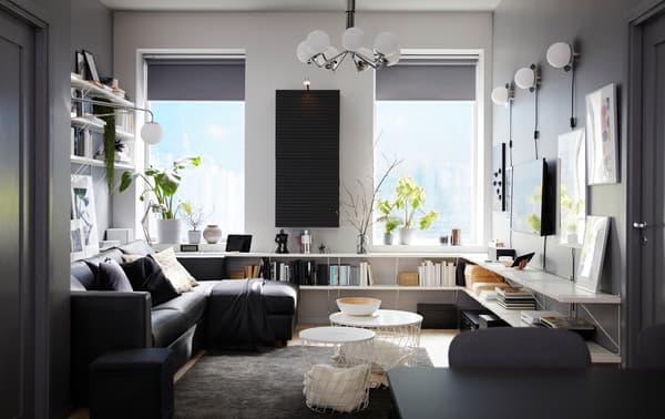 Ruang tamu yang mempunyai katil sofa dengan chaise longue berwarna hitam, para berwarna putih, kabinet lekap dinding antrasit dan ambal berwarna kelabu gelap.