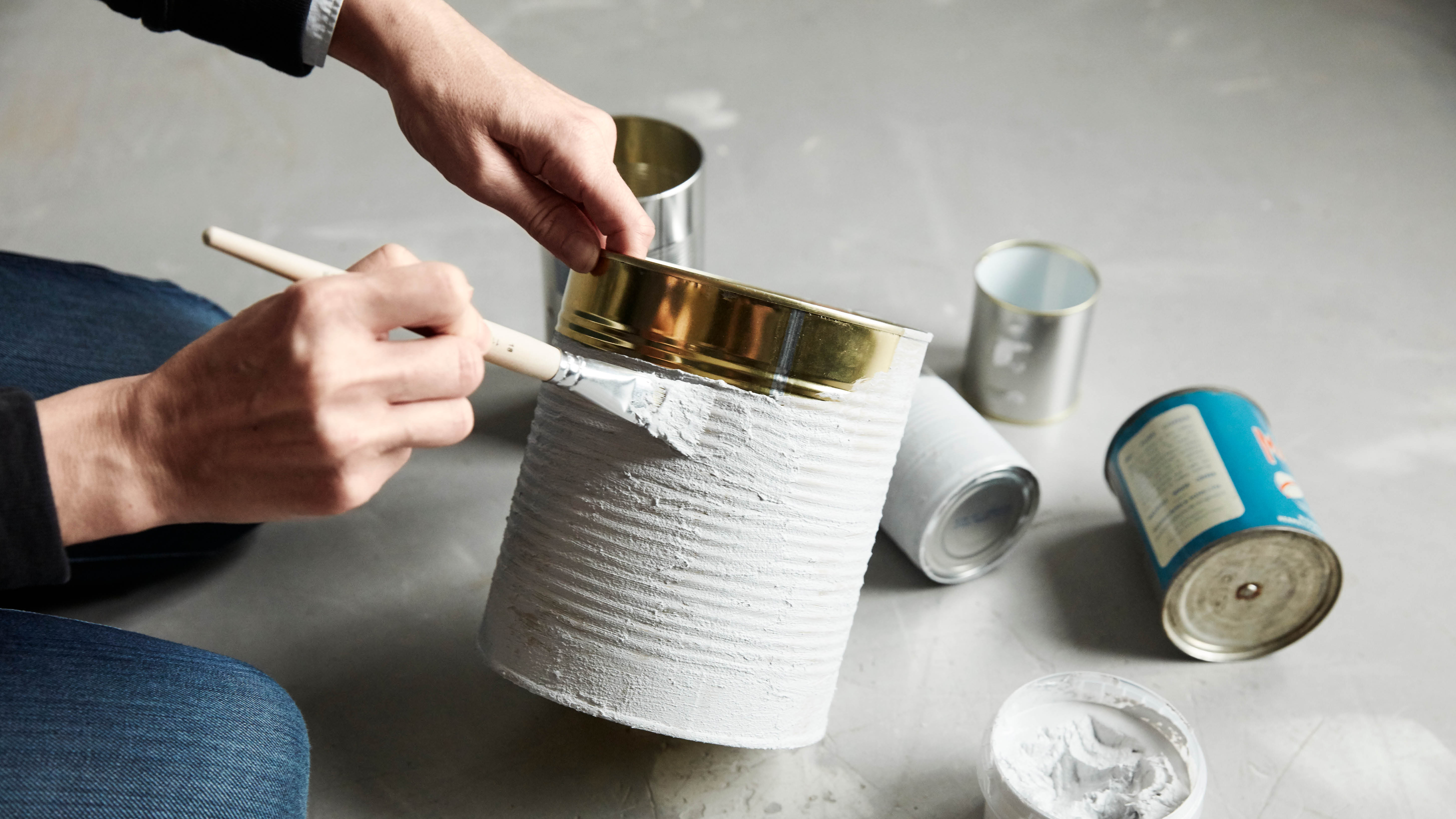 Ruce které přetírají bílou barvou starou plechovku