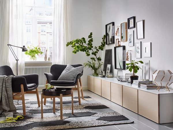 明るい窓際に観葉植物を置いた北欧風リビング。白と木目の家具、グレーのラグでナチュラルな空間。