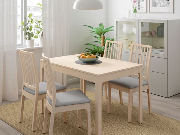 明るい木目のダイニングテーブルと椅子を置いたシンプルな食卓。白い壁と窓辺でナチュラルな雰囲気。