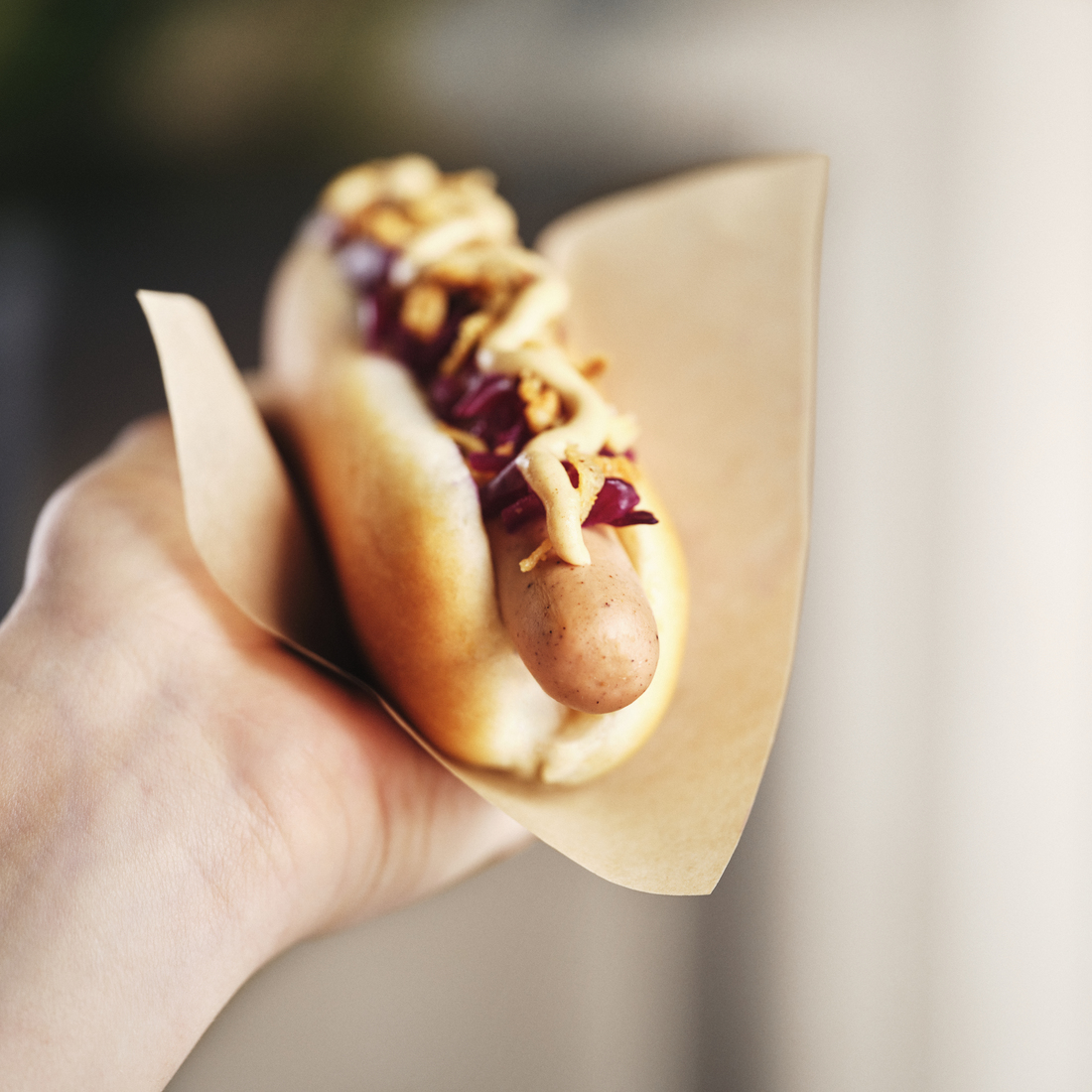 Ruka držící párek v rohlíku z IKEA