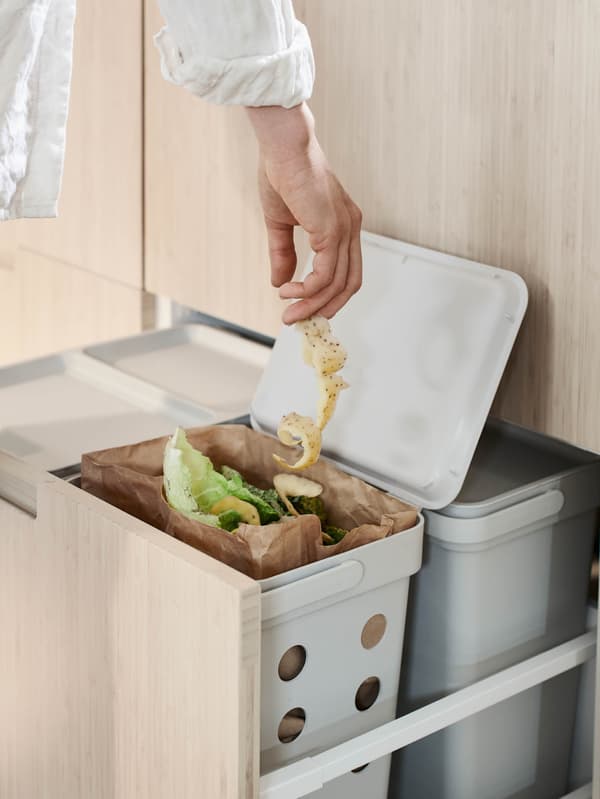 Ruka hádže bioodpad do koša HÅLLBAR.
