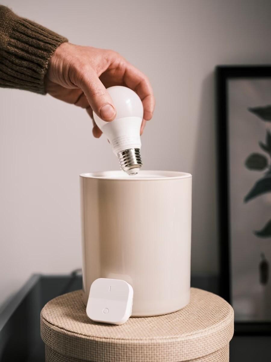 Ruka inštalujúca žiarovku do smart lampy.