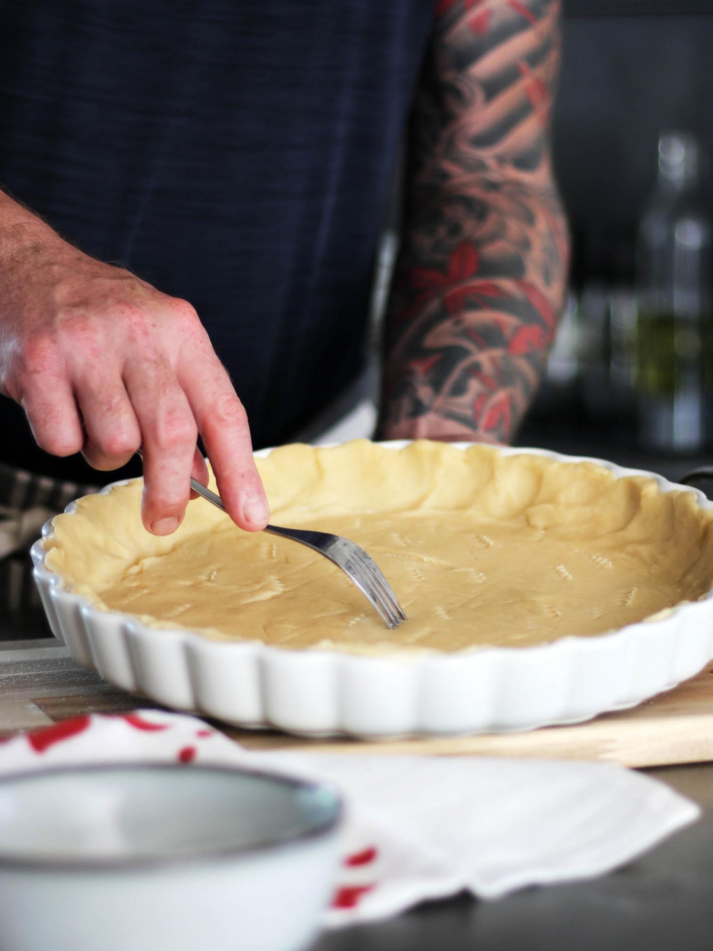 Ruka propichující vidličkou těsto ve formě na koláč VARDAGEN.