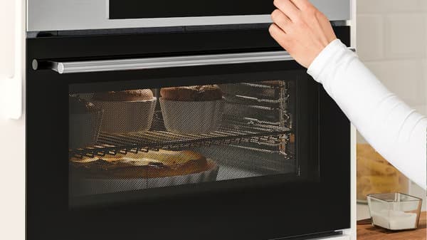 Ruka tiskne tlačítko na mikrovlnné troubě.