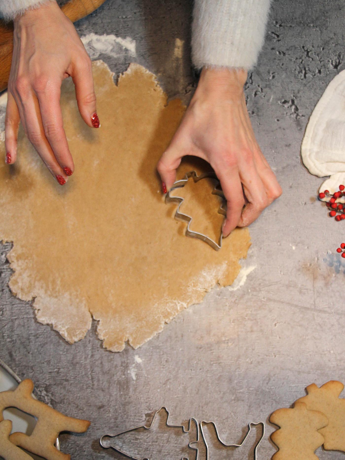 Ruka vykrajuje tvar stromečku z vyváleného těsta vykrajovátkem VINTERFINT.
