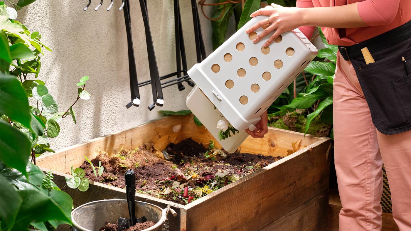 Ruky vysypávajú z koša HÅLLBAR bioodpad do kompostéra.