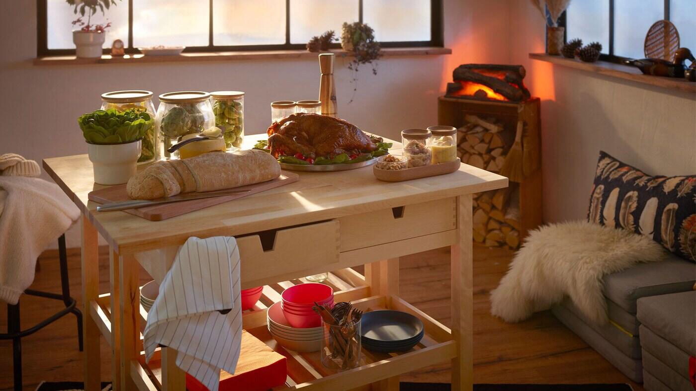 Rum indrettet som en hyggelig bjælkehytte med en lille, festlig buffet anrettet på 2 rulleborde og et kunstigt ildsted i hjørnet.