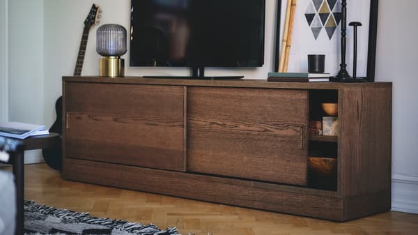 Ruskeaksi petsattu tammiviiluinen TONSTAD-tv-taso, jonka päällä on televisio.