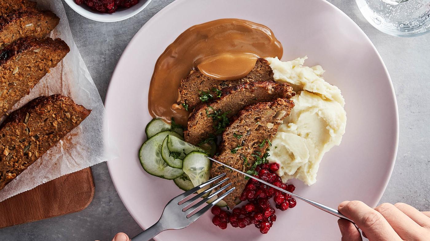 Růžový talíř se sekanou z bezmasé směsi VÄRLDSKLOK přelitou smetanovou omáčkou, bramborovou kaší, brusinkami a nakládanými okurkami.