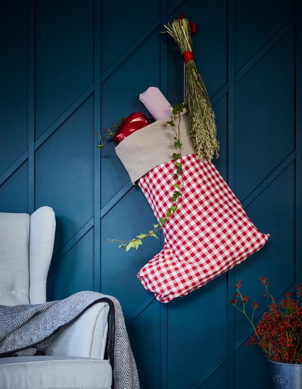 Sac à cadeaux en forme de chausson de Noël, accroché à un mur bleu.