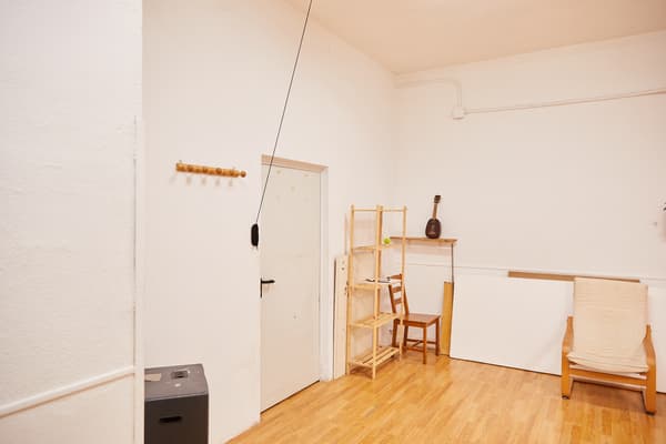 Sala amb porta, penja-robes, prestatgeria, cadires i butaca.