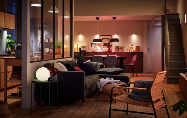 Sala ampla com cozinha. A separação entre o espaço de refeições e a sala é quase impercetível. Sala iluminada por várias fontes de luz.