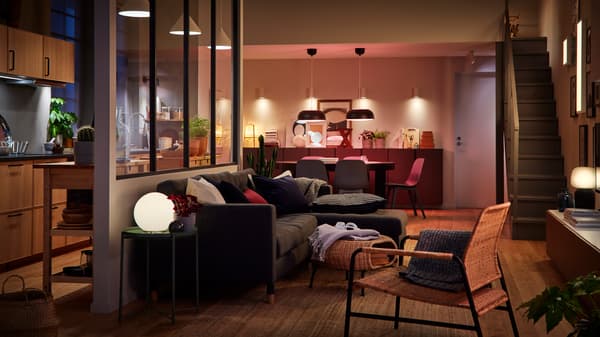 Sala ampla com cozinha. A separação entre o espaço de refeições e a sala é quase impercetível. Sala iluminada por várias fontes de luz.
