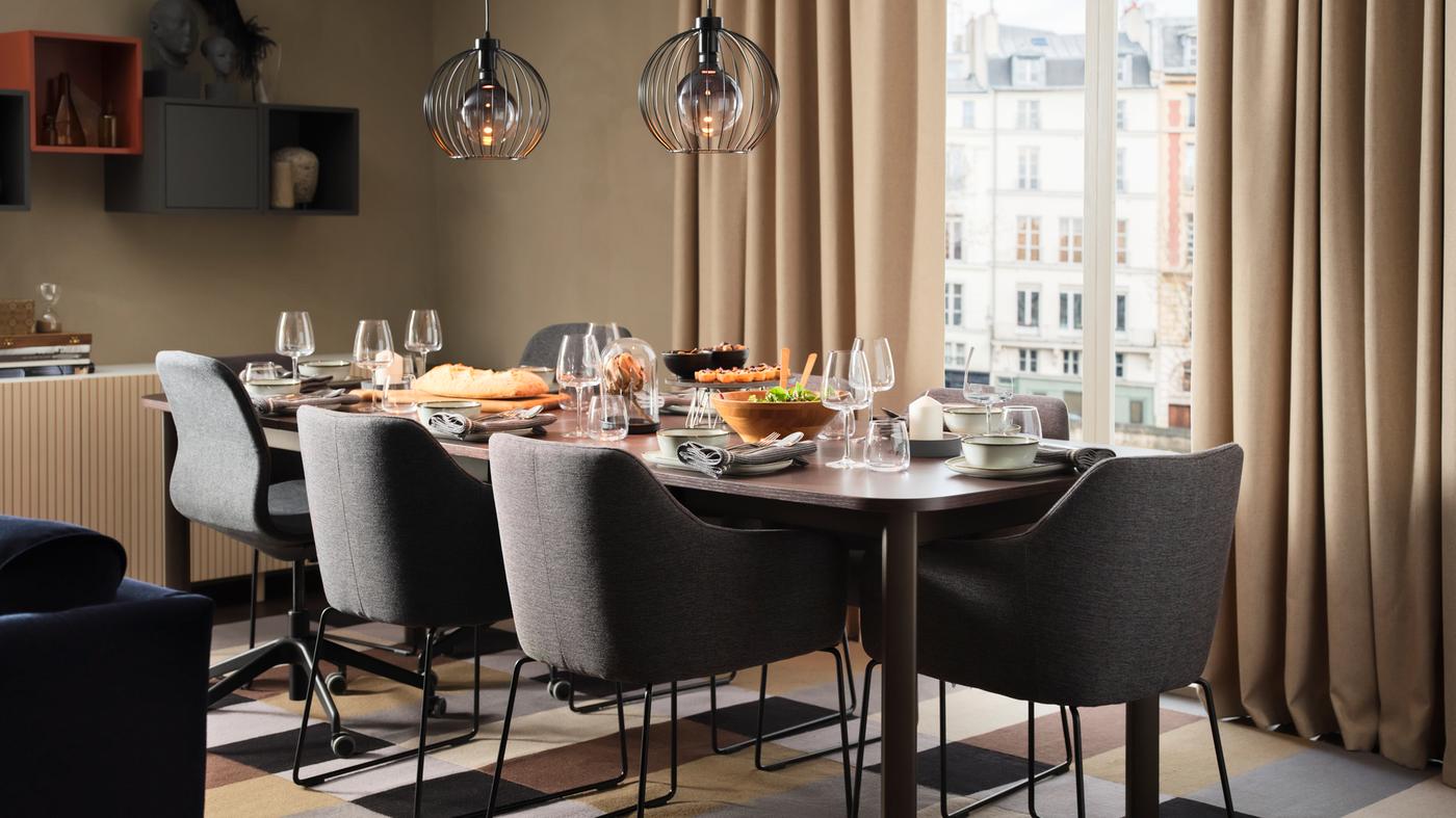 Sala bege com uma mesa extensível STRANDTORP posta para uma refeição, rodeada por cadeiras TOSSBERG e LÅNGFJÄLL.