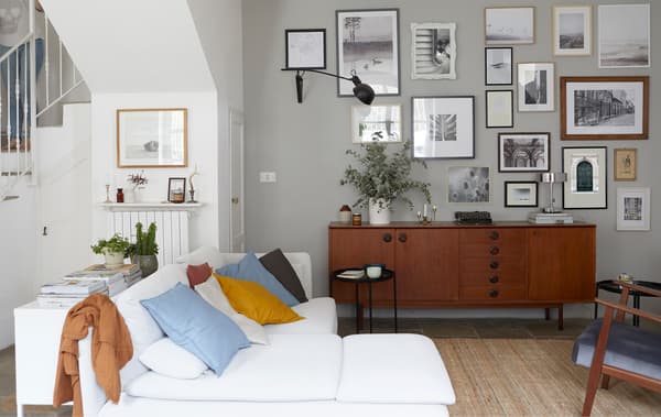 Sala da pranzo con divano ad angolo bianco, buffet in legno scuro e foto appese alle pareti - IKEA