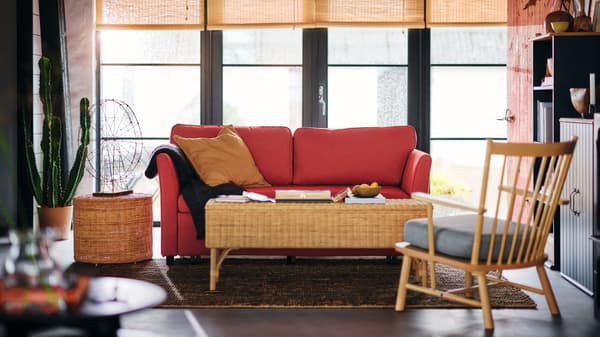Sala de estar con sofá rojo, mesa de café y sitial café con cojín gris.